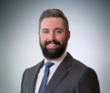 Image of Matt Berger wearing a white shirt, grey suit, and navy tie.